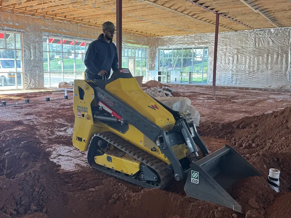 Track loader grading the floor of a unit being fitted out